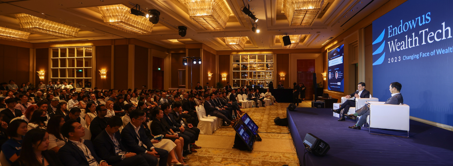 Large audience at Endowus Wealth Tech conference with speakers on stage and screen display.